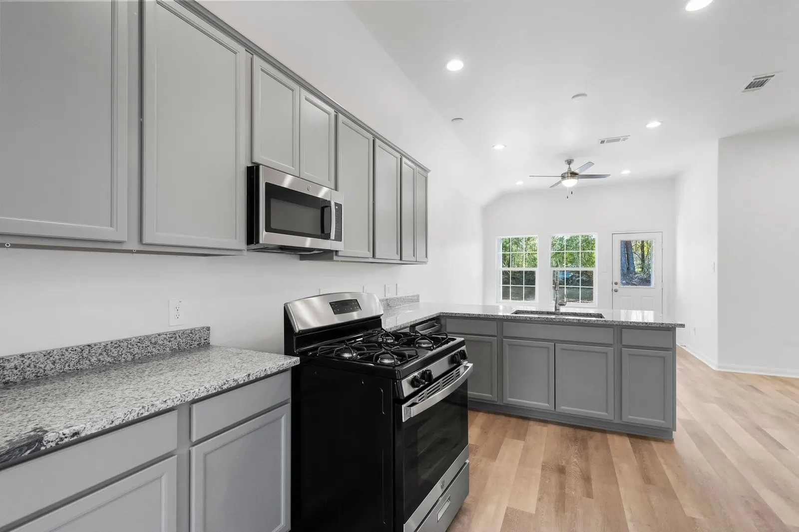 Kitchen with gas range and grey cabinets at Cedar Crossing by Alta Homes